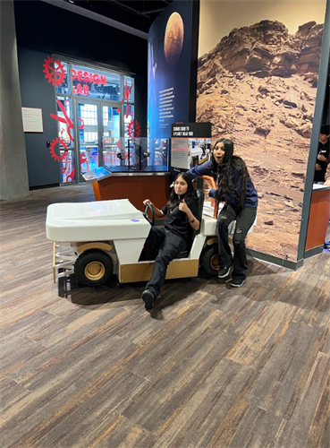 two students on a moon rover with a fake background of space